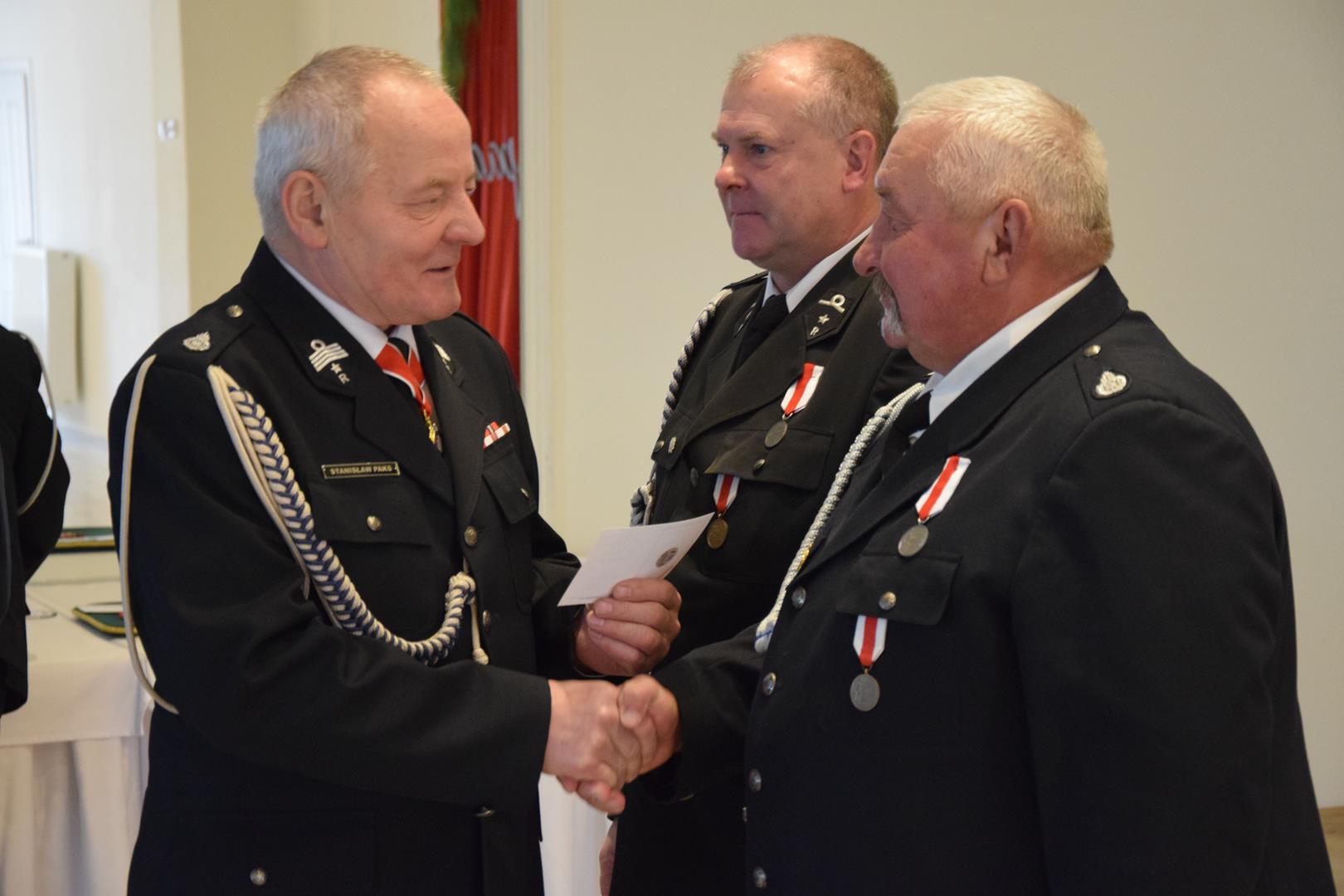 Zdjęcie przedstawia moment przyznania odznaczeń