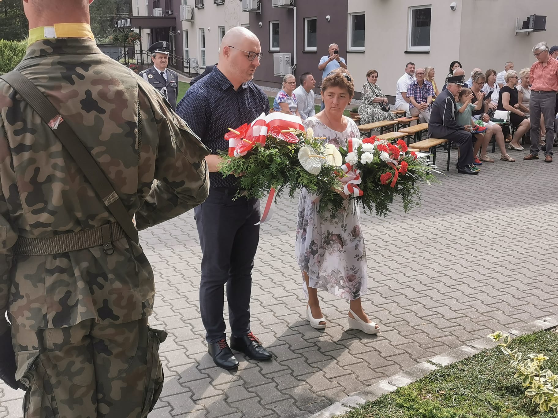 Zdjęcie przedstawiające składanie kwiatów pod pomnikiem