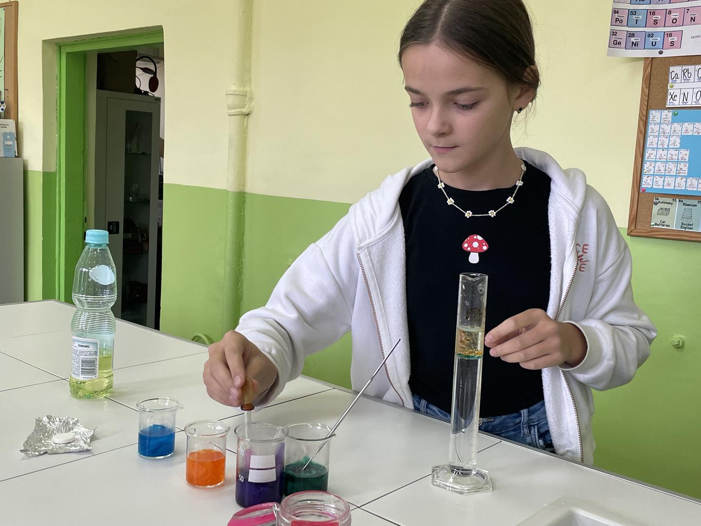 Zdjęcie przedstawia dziewczynkę przeprowadzającą eksperymenty
